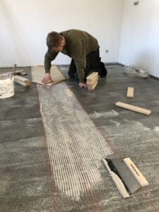 Mand lægger trægulv med lim i rum